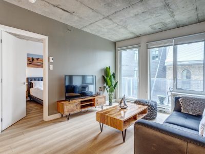 Spacious and modern living room in a fully furnished apartment by Montreal Stays, featuring comfortable seating, large windows, stylish décor, and ample natural light in Montreal.